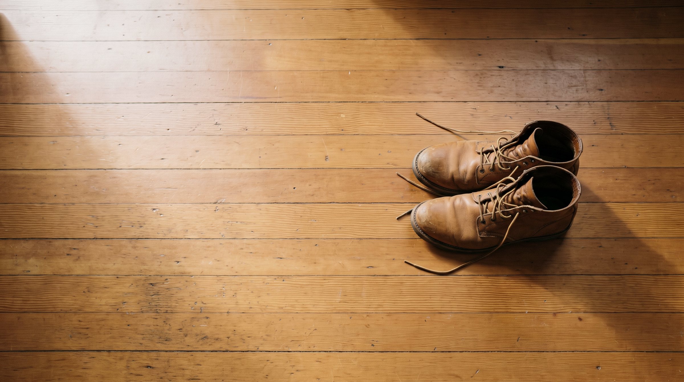 A pair of work boots left side by side on a fir floor, just off the drop sheet